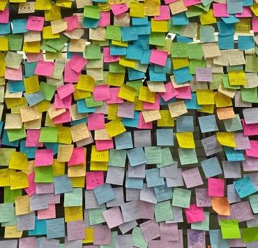 Parete ricoperta di post-it colorati, metafora dei diversi significati nascosti dietro le parole e le obiezioni nel marketing
