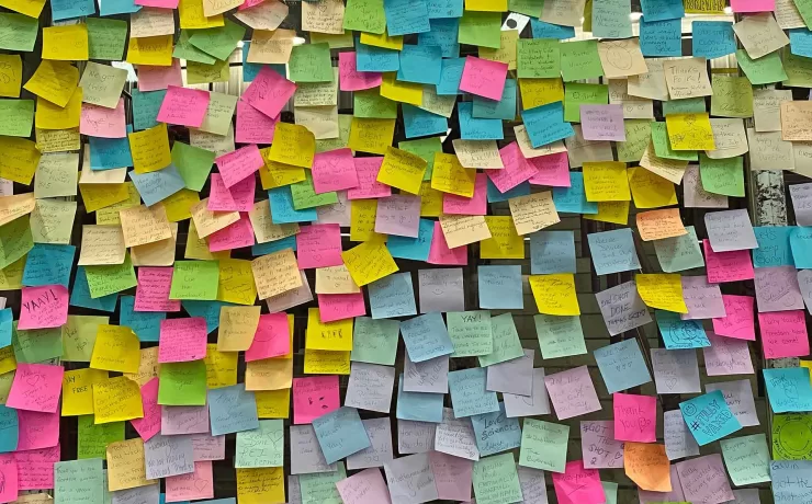 Parete ricoperta di post-it colorati, metafora dei diversi significati nascosti dietro le parole e le obiezioni nel marketing